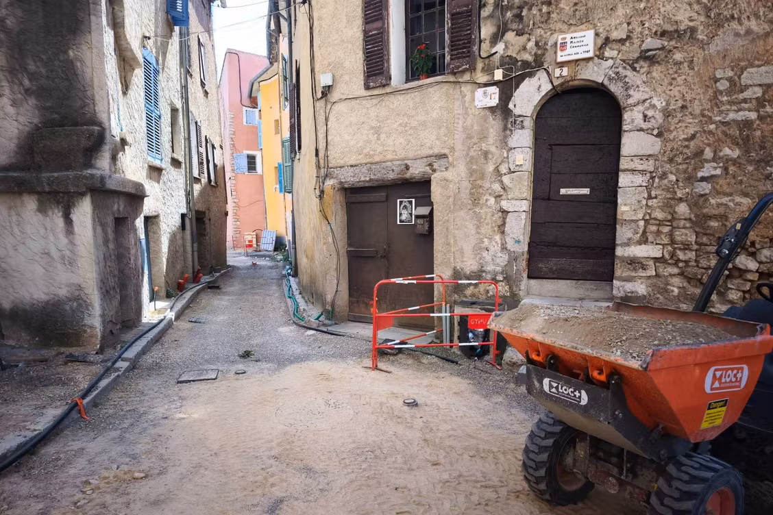 Ruelle d'un village provençal en travaux, bordée de maisons en pierre